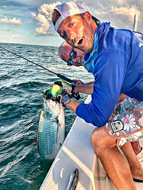 Angler holding a tarpon beside the boat at sunset in Key West
