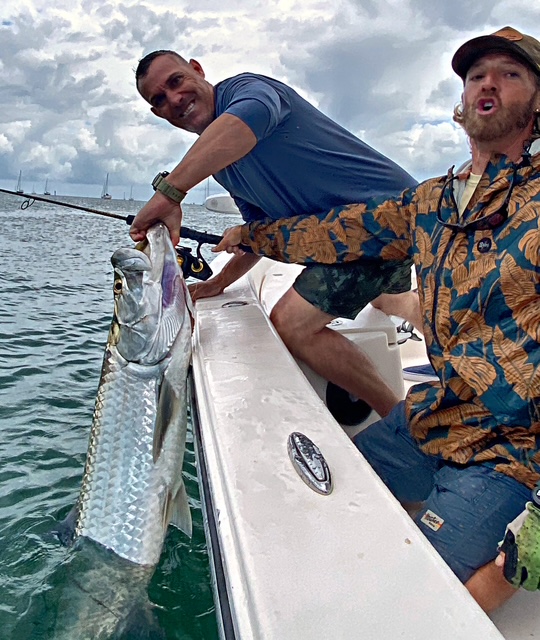 Two anglers with a tarpon under a cloudy Key West sky