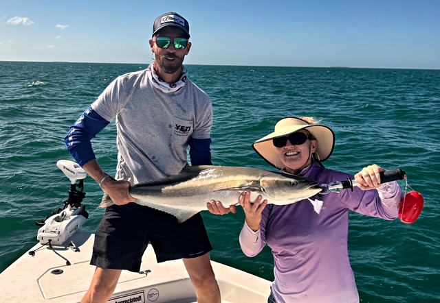 Guest in a sun hat holding a cobia on a Key West charter