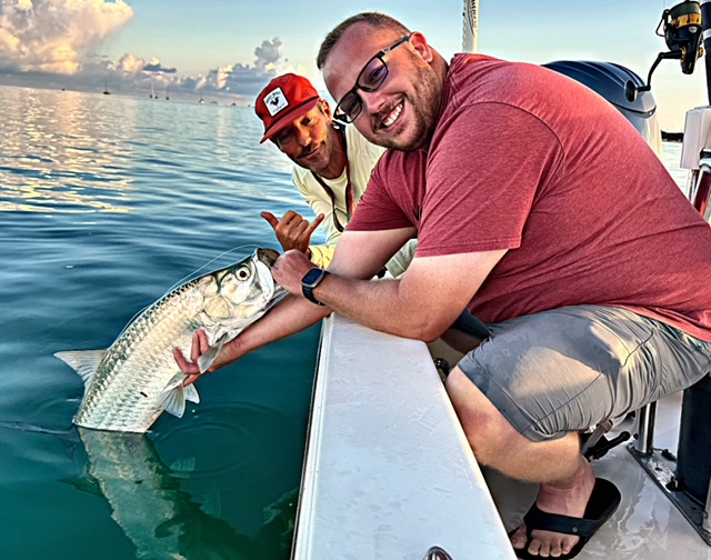 Guest and captain with a tarpon boatside at sunset in Key West