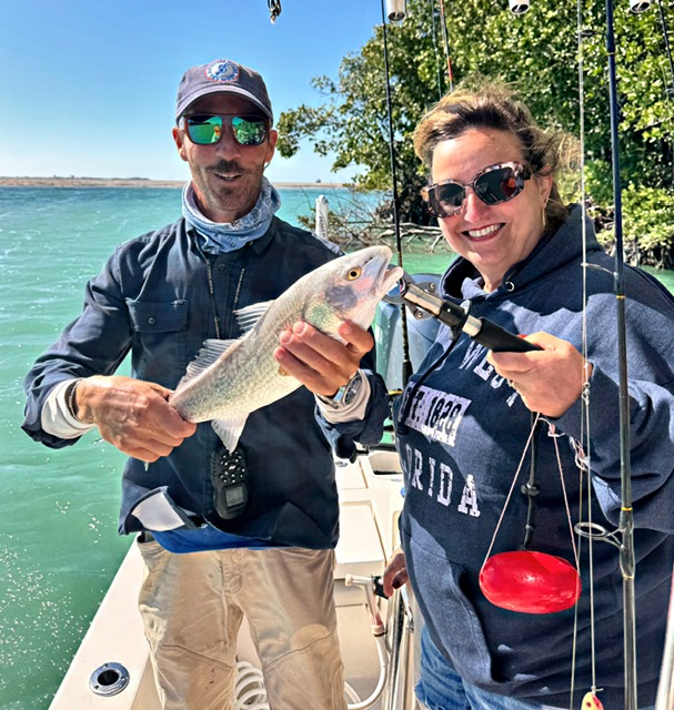 Guest and captain holding a snapper along a mangrove shoreline