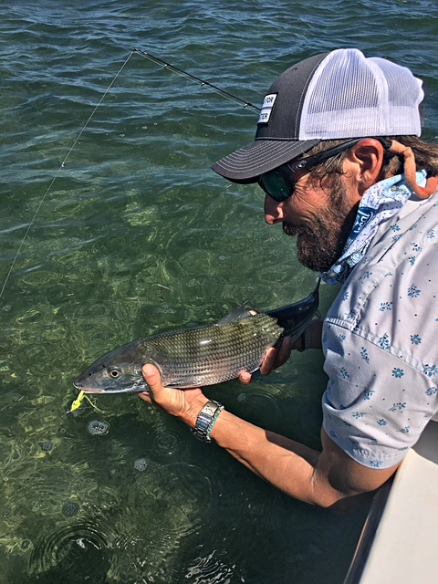 Captain reviving a bonefish in shallow water beside the boat
