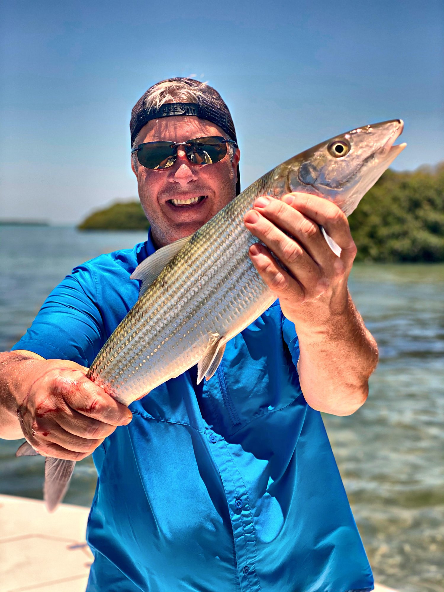 Angler holding a bonefish along a Key West mangrove shoreline
