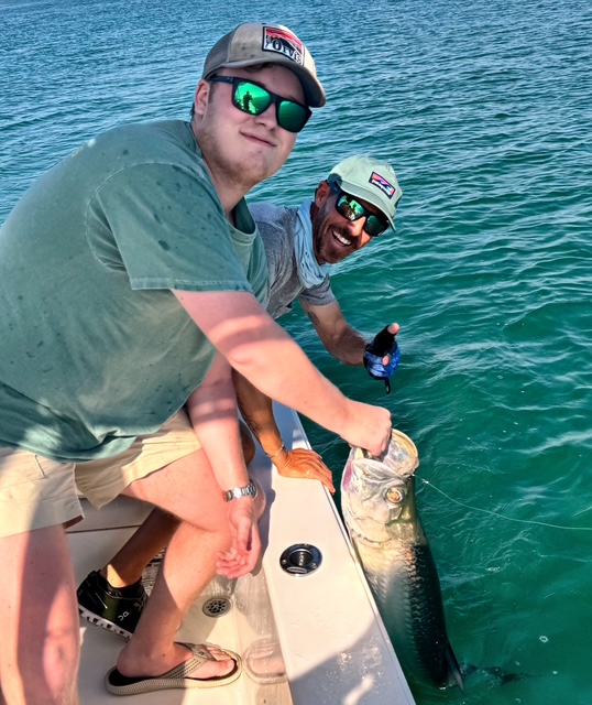Two guests leaning over the gunwale with a tarpon in Key West