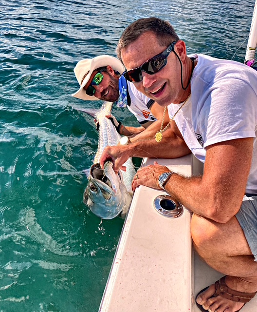 Smiling guest with a tarpon at the boat's edge in Key West