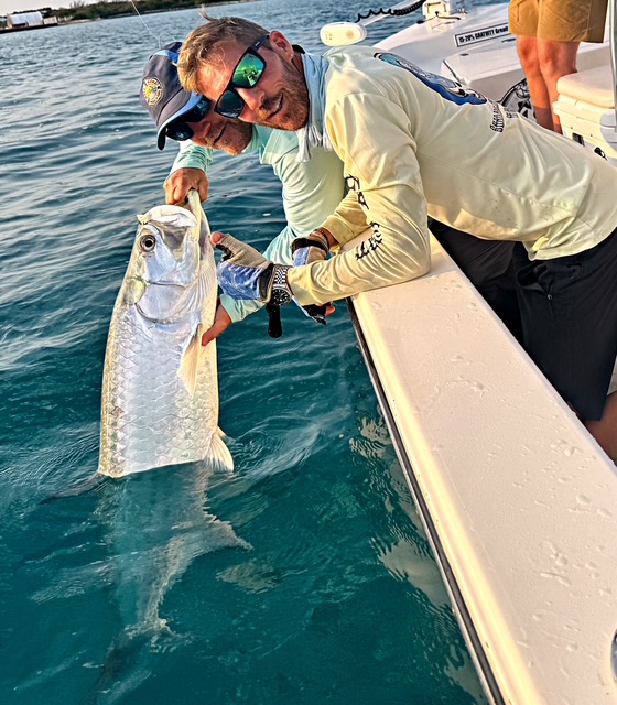 Capt. Juice holding a tarpon upright beside the boat before release