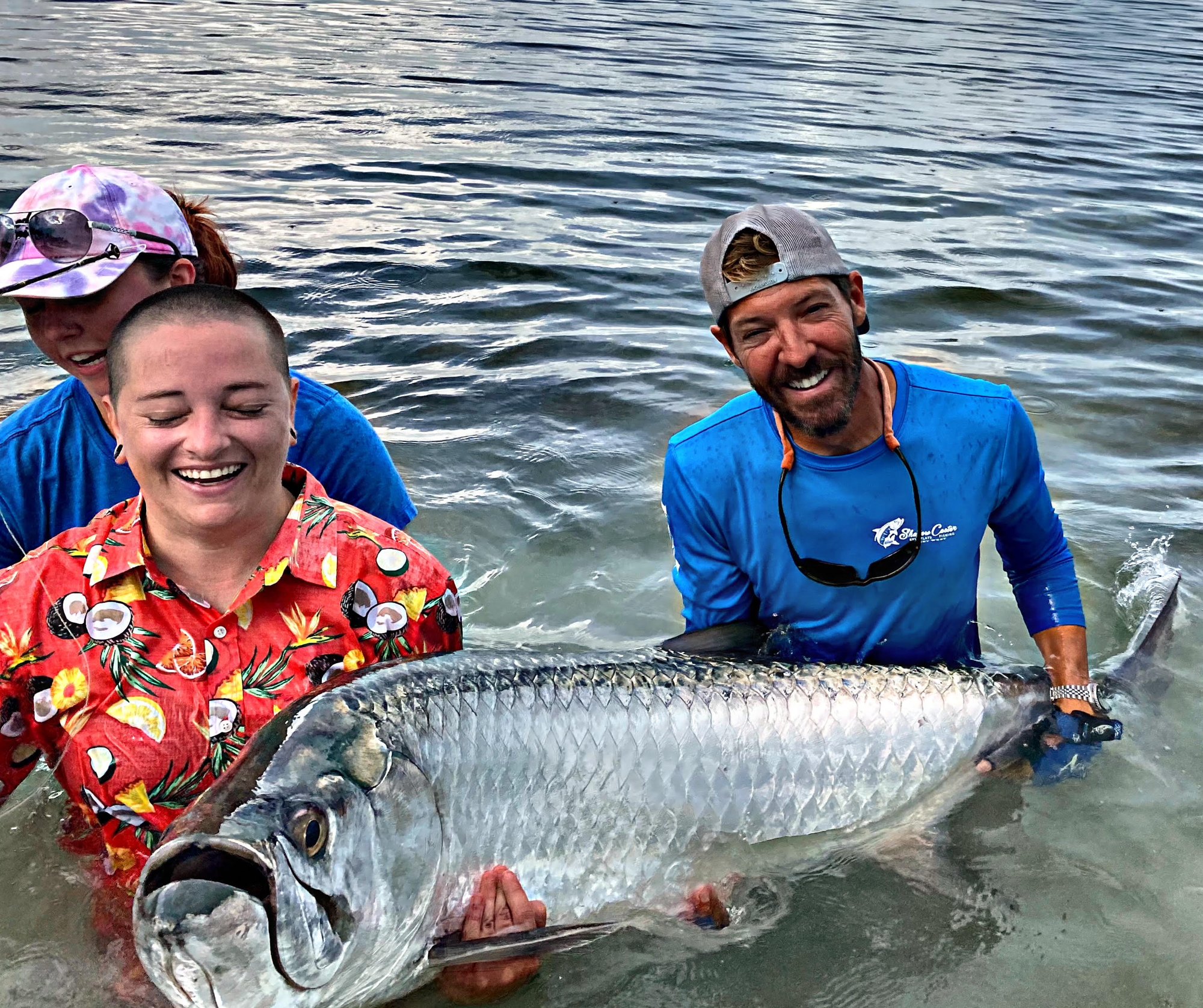Guests and captain holding a tarpon in the water for release in Key West