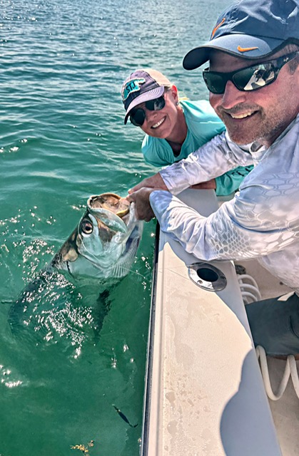 Two guests smiling as a tarpon is released boatside in Key West