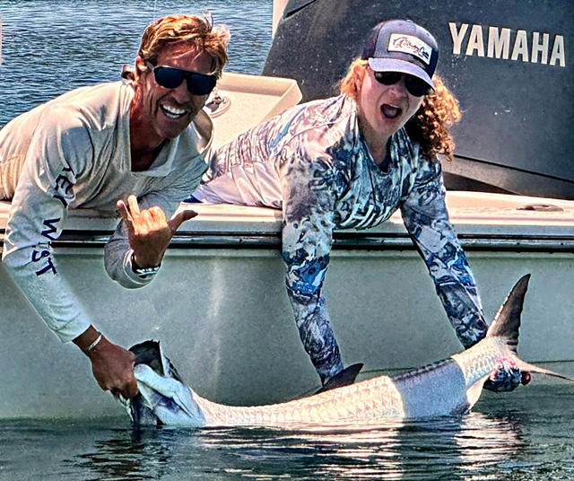 Captain and guest laughing while releasing a tarpon at the boat