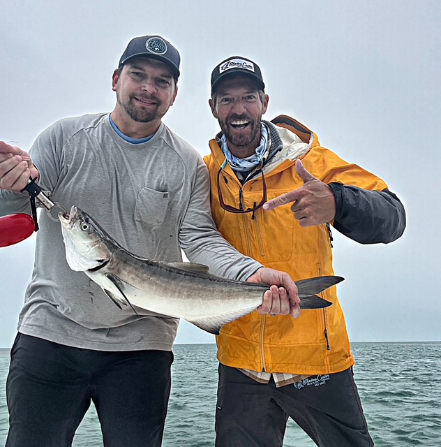 Two anglers with a cobia on a grey Key West morning